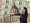 Lawmaker stands in front of City Hall with a backdrop of dollar bills.