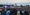 Thousands of people watch a man in a white outfit sing on an outdoor festival stage.