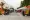 Roughly 10 pop-up canopies line a parking lot with dozens of people interacting with each one. 