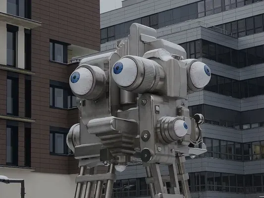 A robot sculpture covered in moving eyeballs sits in a public space in Prague.