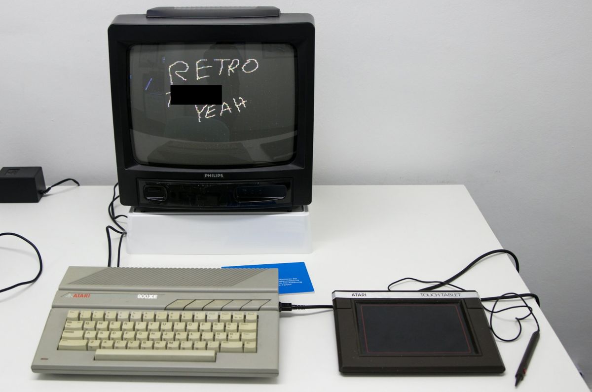 Retro computer computer with drawing pad on desk, the monitor reads "RETRO [censored] YEAH"