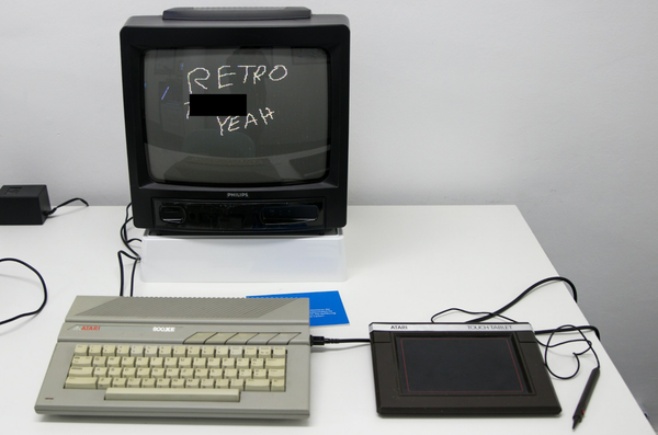 Retro computer computer with drawing pad on desk, the monitor reads "RETRO [censored] YEAH"