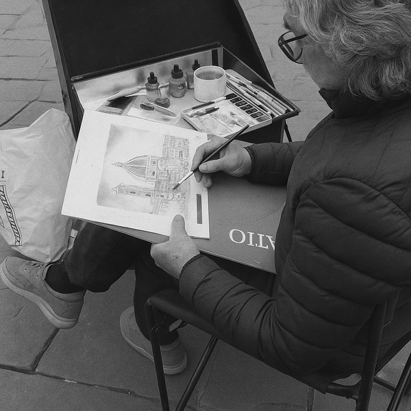 An artist paints a watercolor of a city.