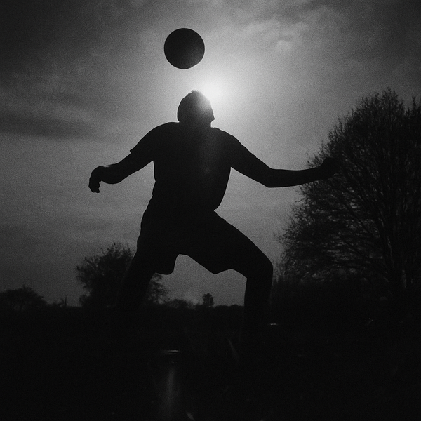 silhouette of man heading a football on grass field during sunset