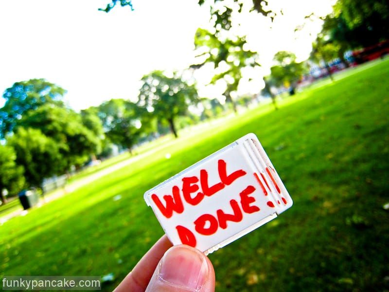 Some fingers holding up a badge saying 'well done'