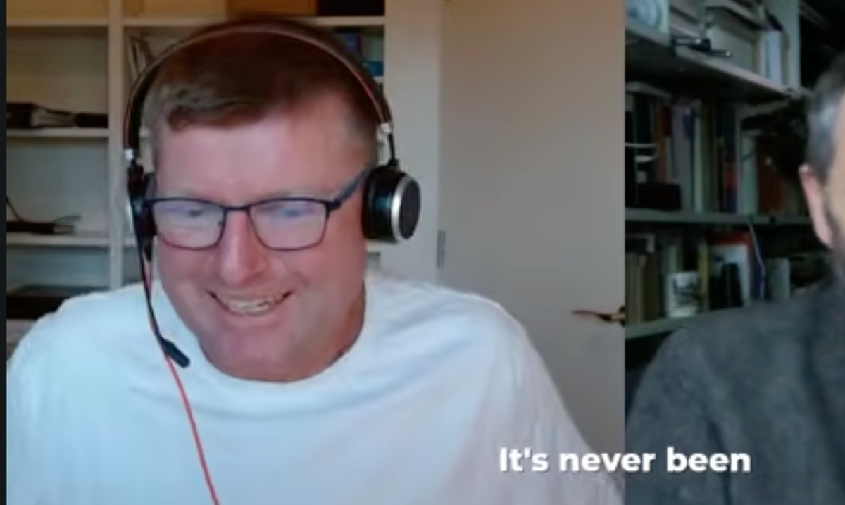 A screengrab from a YouTube video. Tom Loosemore in a white t-shirt and headset with the caption 'it's never been' visible