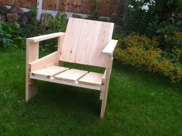 A home made wooden chair sitting on a lawn