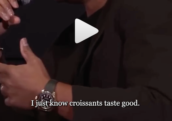 Close up of a hand and a watch with the words 'I just know croissants taste good' superimposed. And a big play button. It's a screengrab from a video