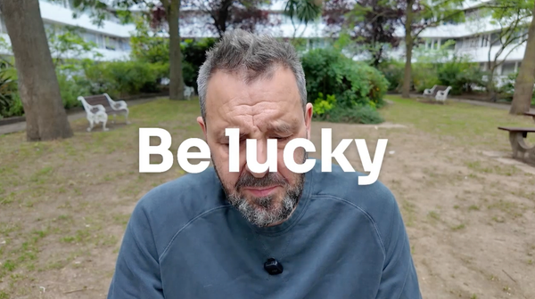 A video screengrab. A man with head bowed and the caption 'be lucky'