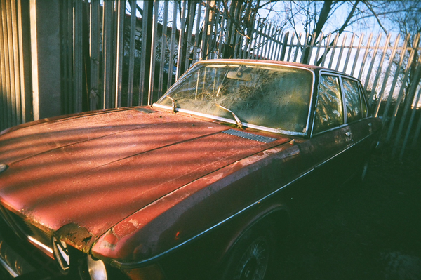 A rusty, and red, BMW that's been abandoned