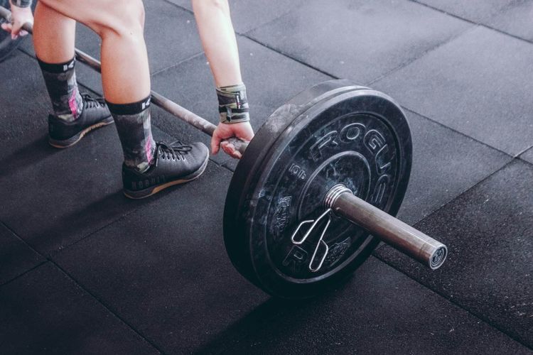 A man is at the gym standing and ready to lift a barbell. 