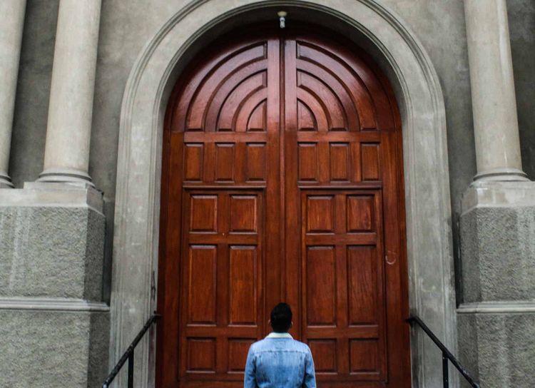 A man looking a big brown wooden door.