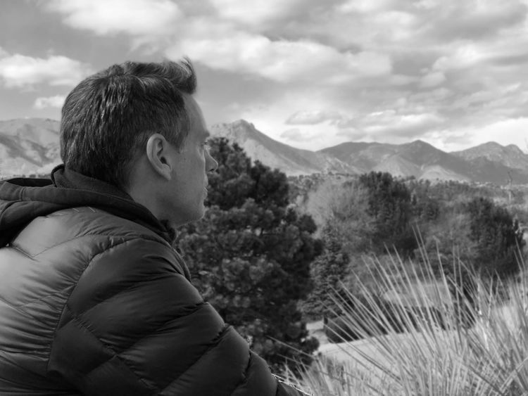 A black and white photo of me in a jacket overlooking the mountains of Colorado.