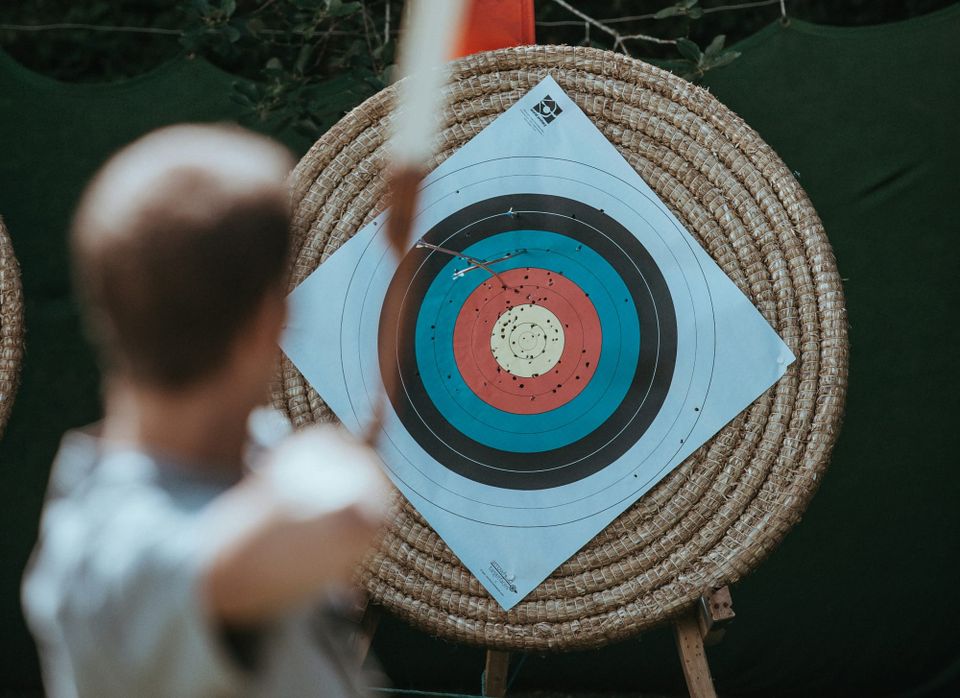A man with a bow is aiming at the bulleye.
