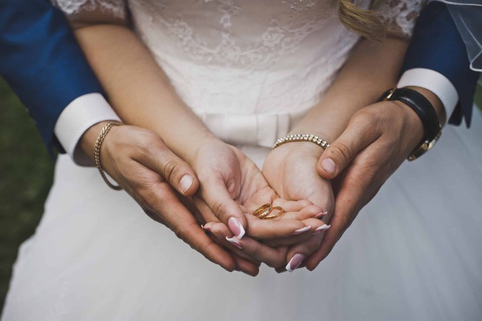 A newly married couple are showing their hands and their rings.