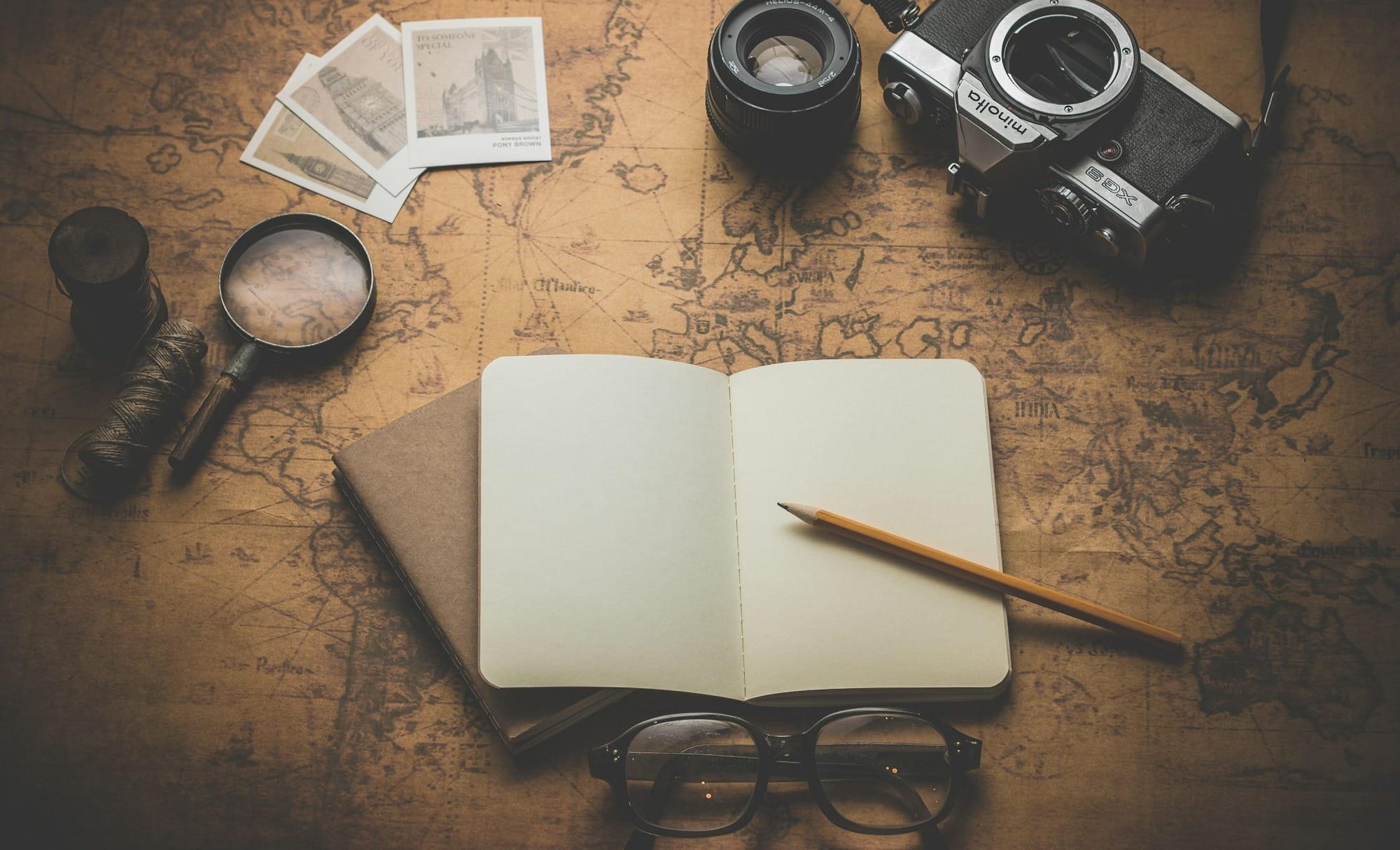 flat ray photography of book, pencil, camera, and with lens