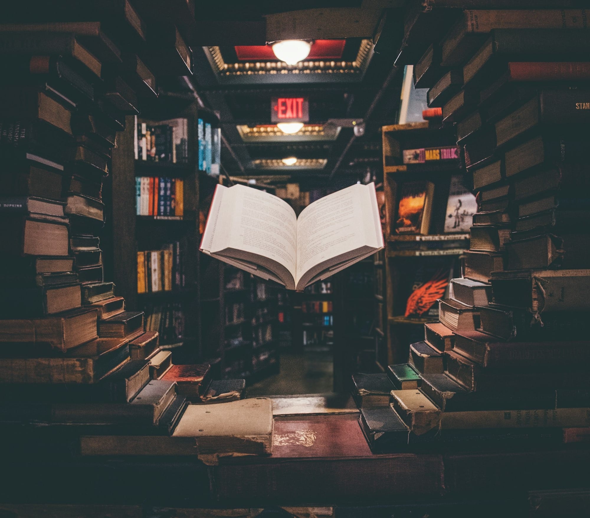 view of floating open book from stacked books in library