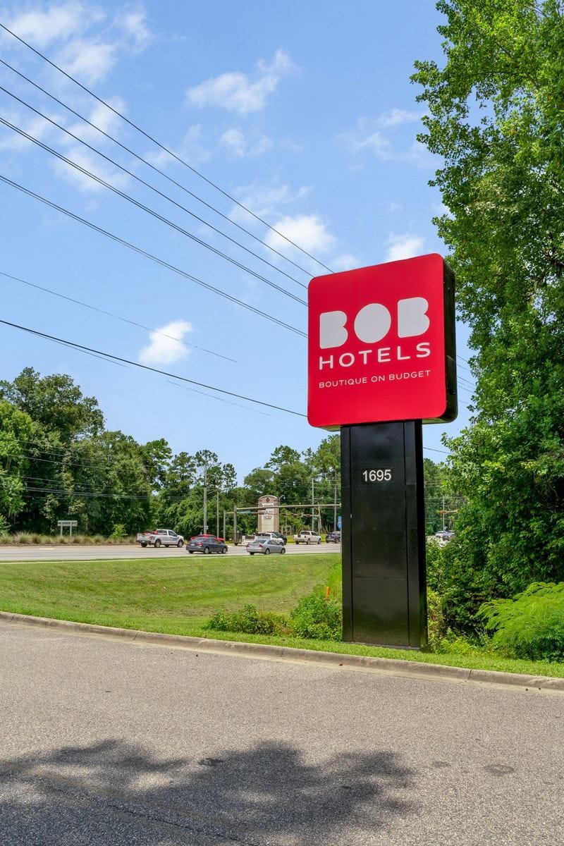 The red BOB Hotels roadside sign on Capital Circle under a blue sky