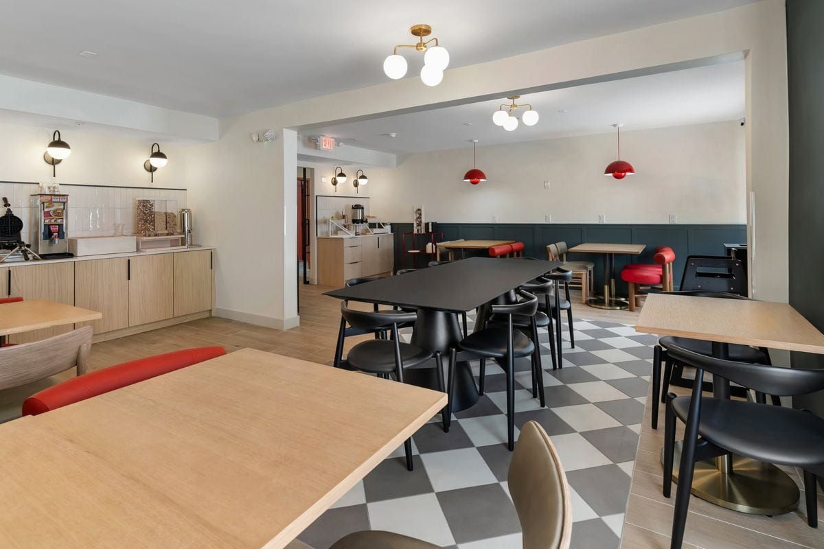 The café dining area at BOB with long tables, red pendant lights and a checkerboard floor