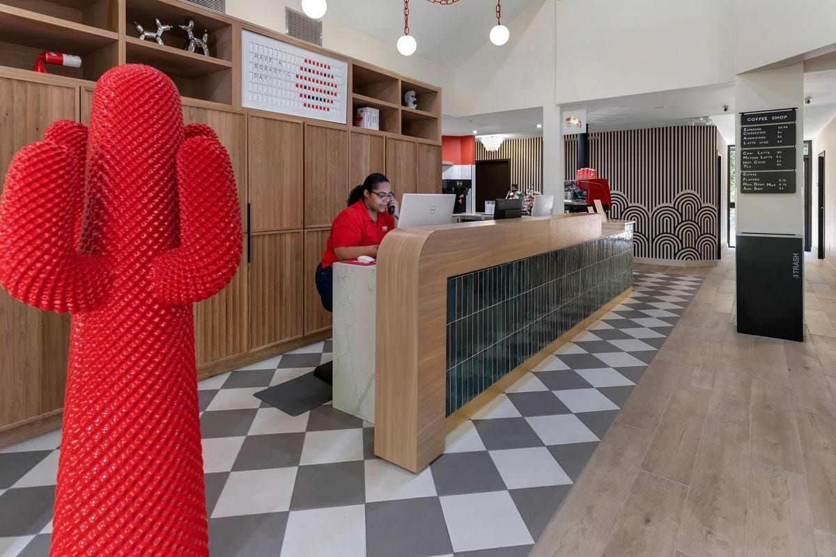 A smiling host at BOB's front desk, next to a giant red cactus sculpture