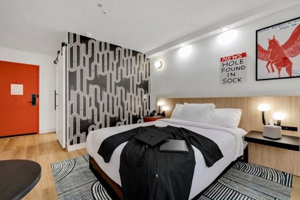 A black graduation gown, cap and diploma cover laid on a King bed at BOB Hotels Tallahassee (AI-assisted image based on a real BOB room photo)
