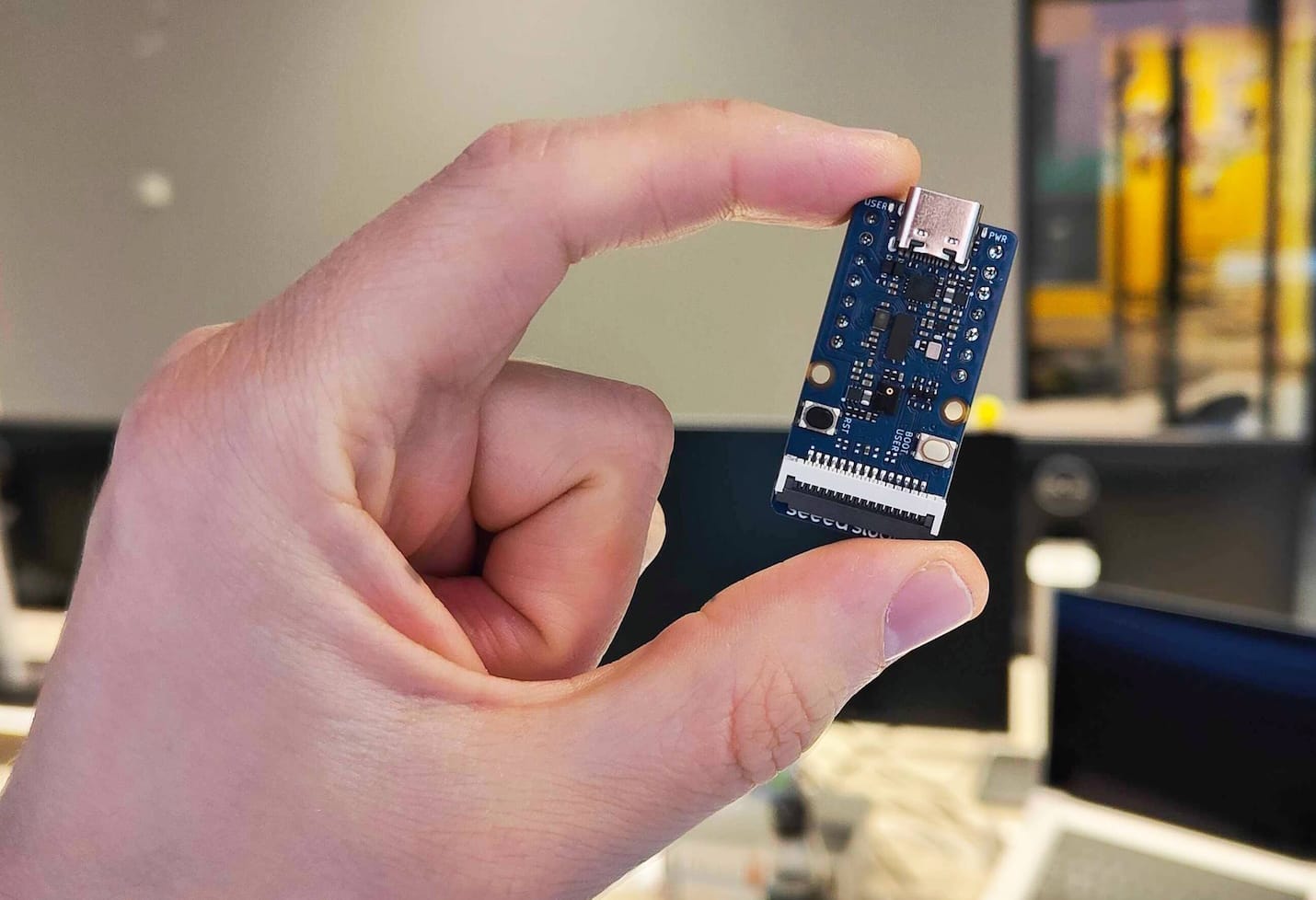Hand holding a small microcontroller.