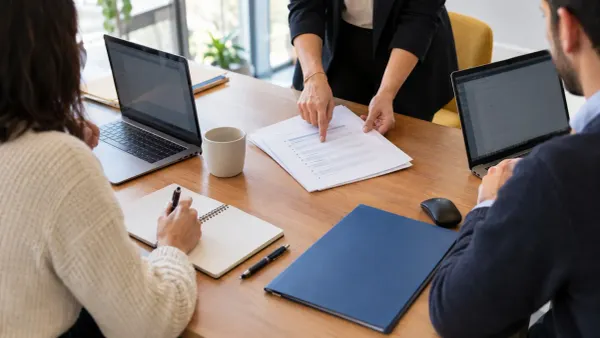 Tre colleghi in ufficio consultano documenti e un laptop per organizzare il registro privacy.