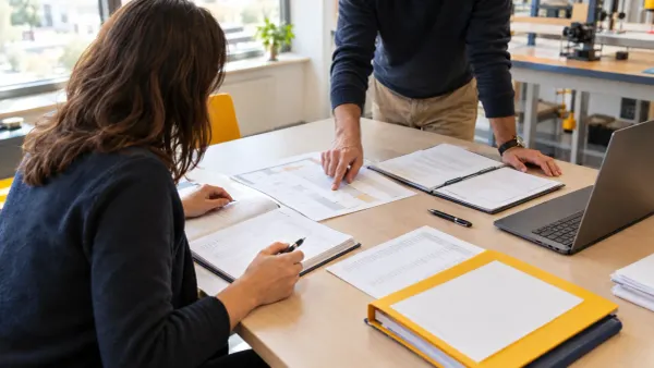 Tutor scolastico e collega controllano documenti PCTO su una scrivania di istituto tecnico