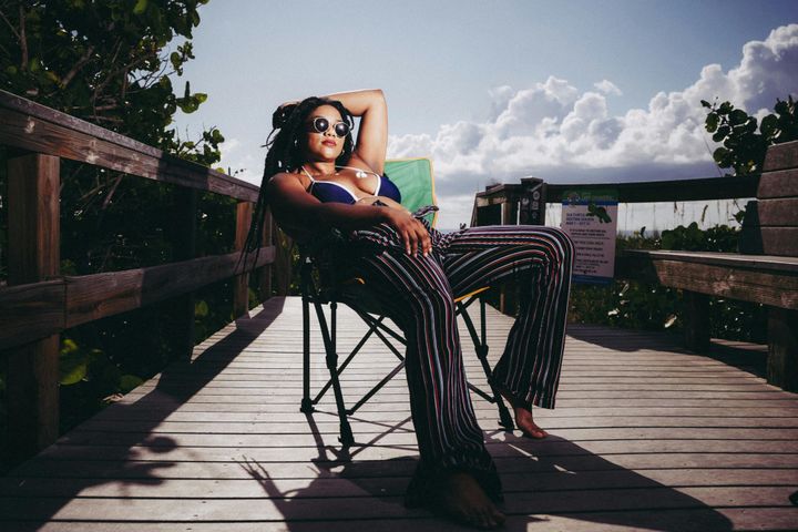 woman in shades laying back in the sun on a wooden pier