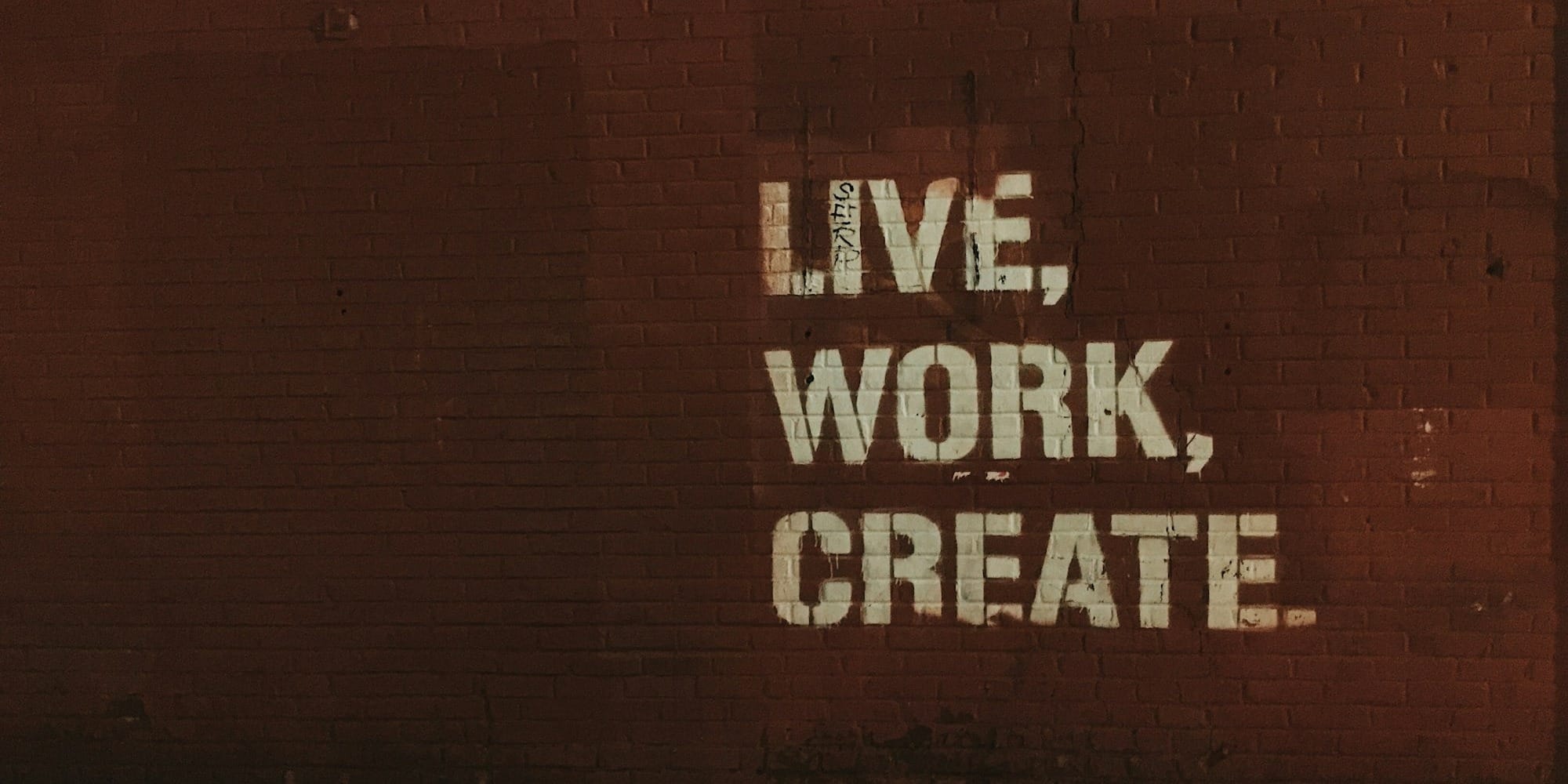 red brick wall with live, work, create. quote