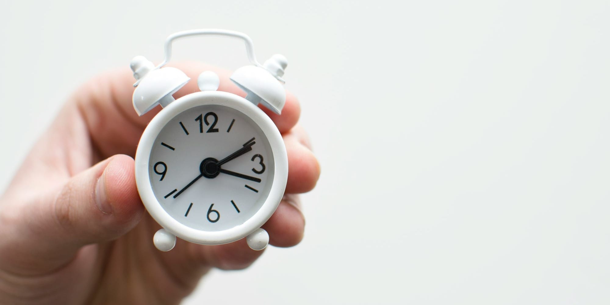 person holding white mini bell alarmclock