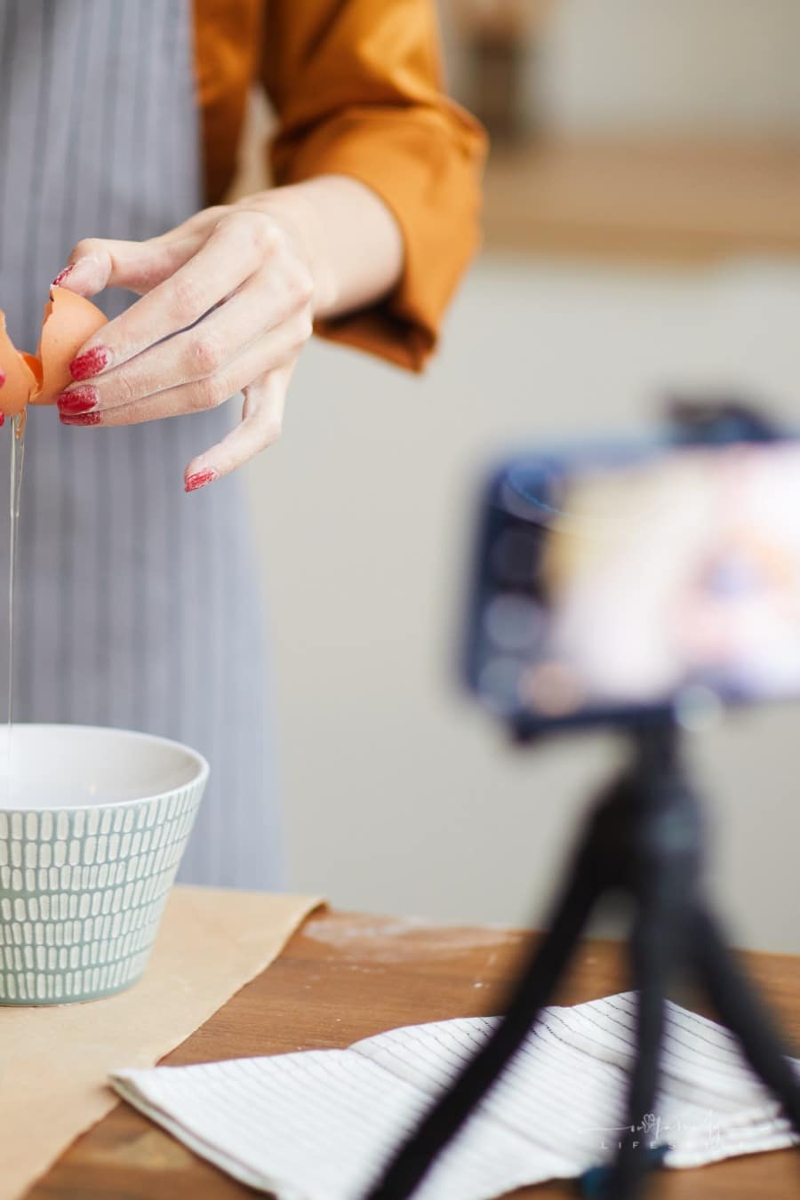 woman cracking open eggs into bowl while filming baking video