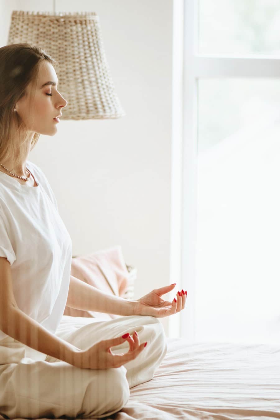 Young woman practicing meditation on bed