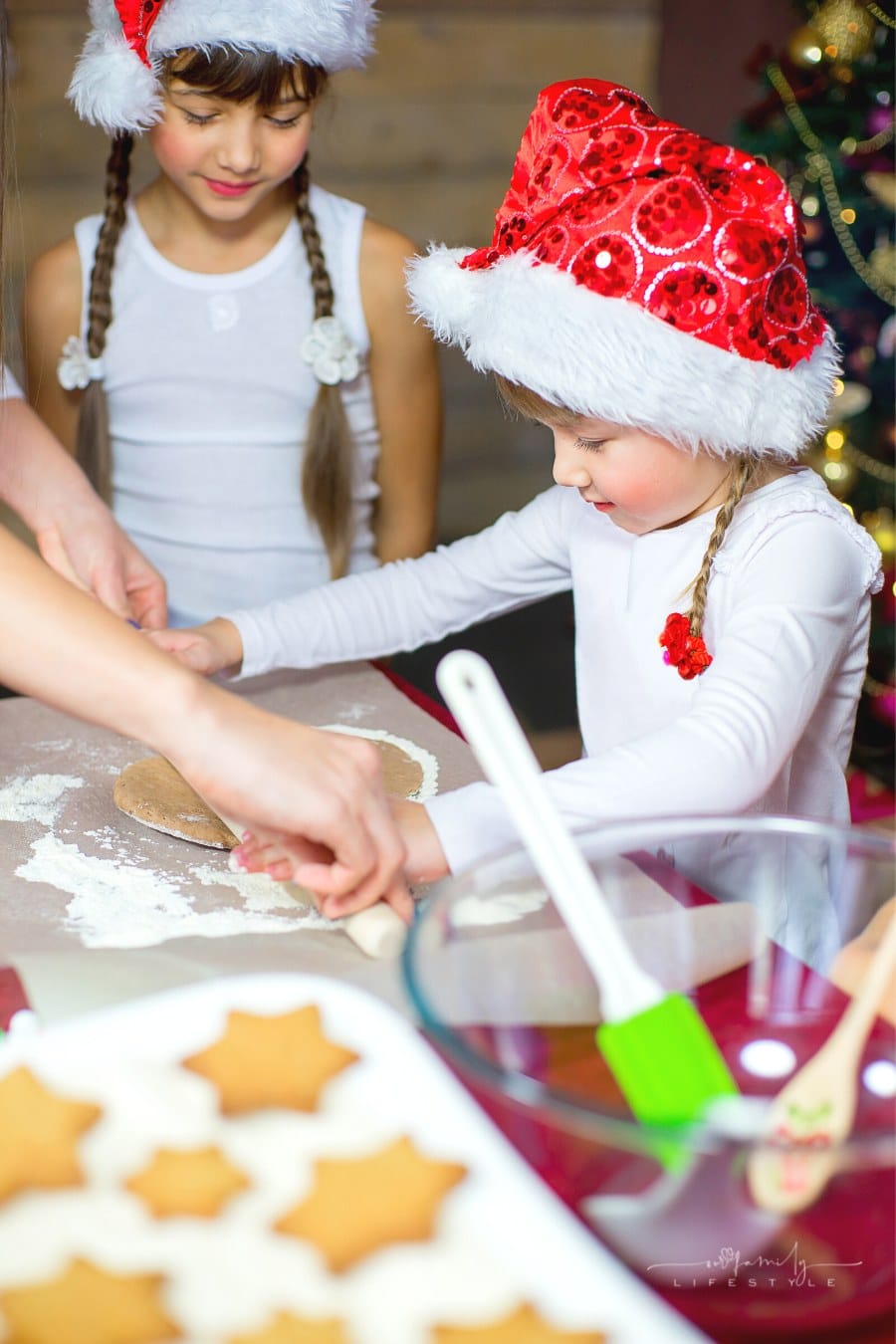 kids baking Christmas cookies while wearing Santa hats