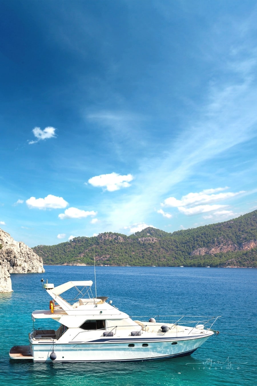 yacht moored off the coast with the sea and mountains in the background