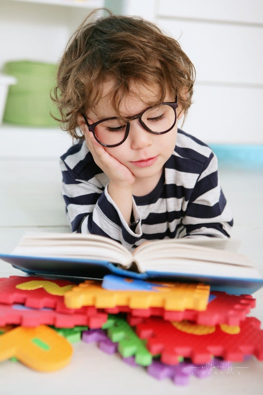 toddler boy reading book wearing glasses