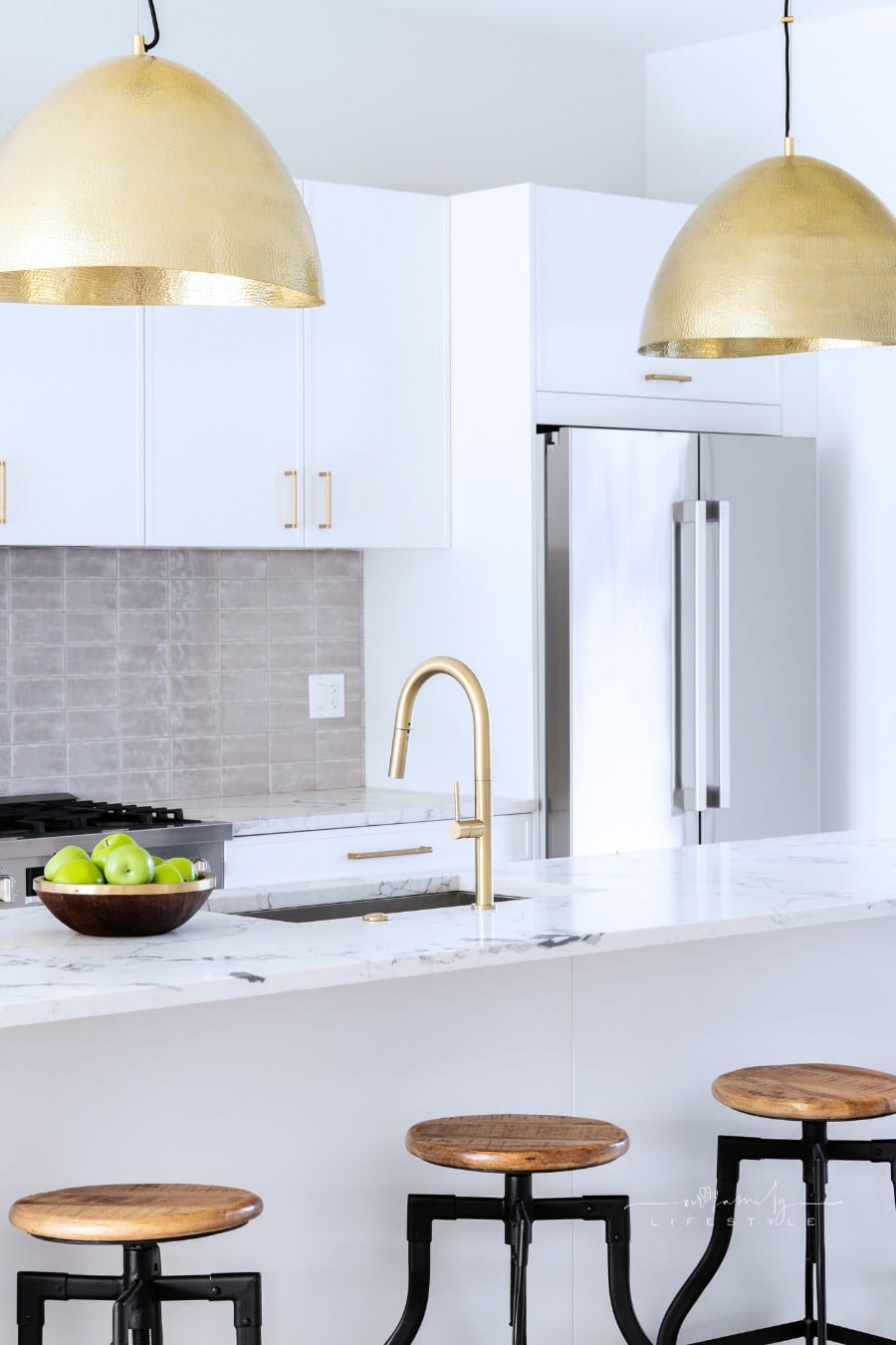 gold pendant lights hanging over a white kitchen island