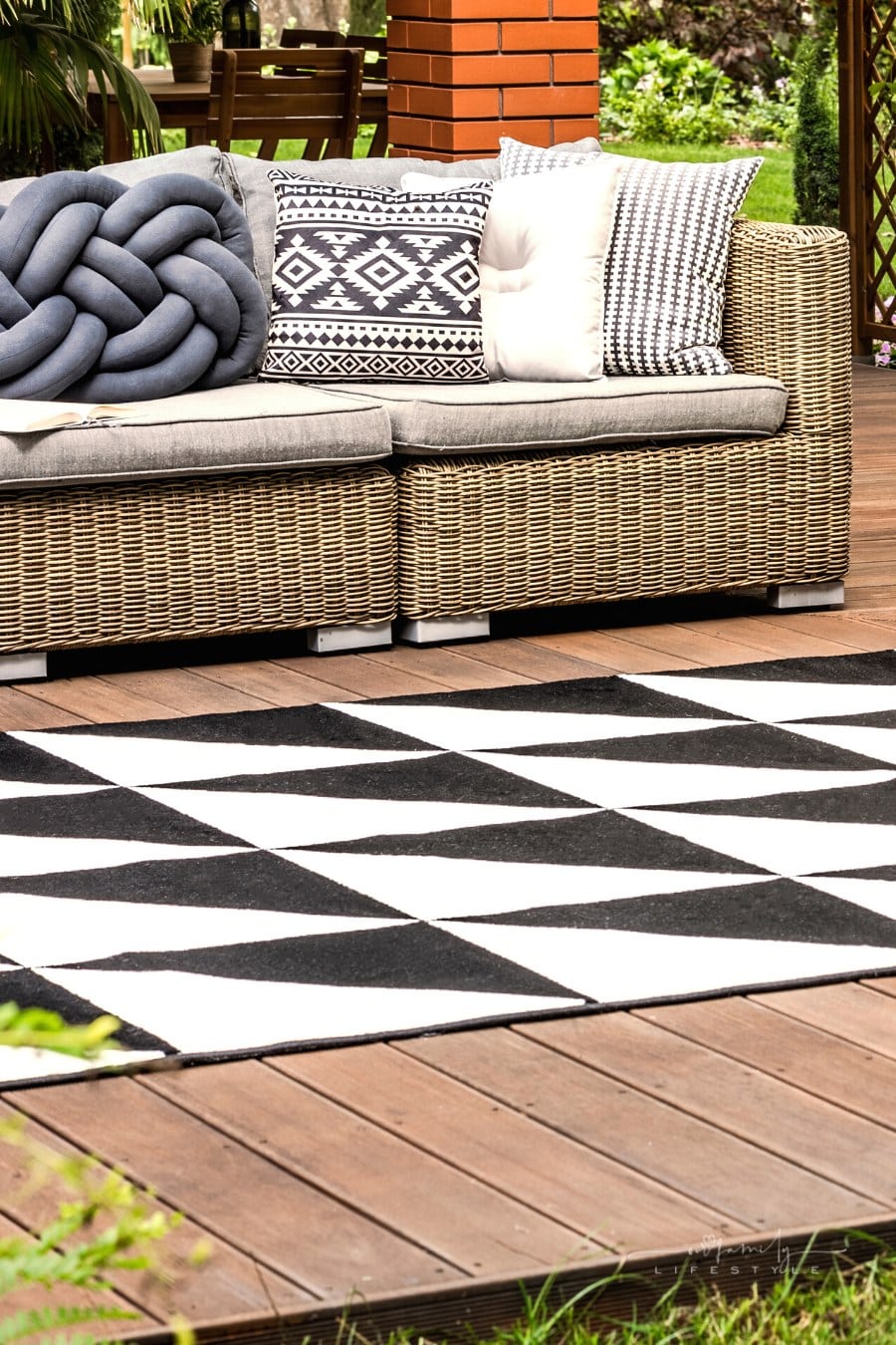 wicker couch and geometric outdoor rug on wooden patio