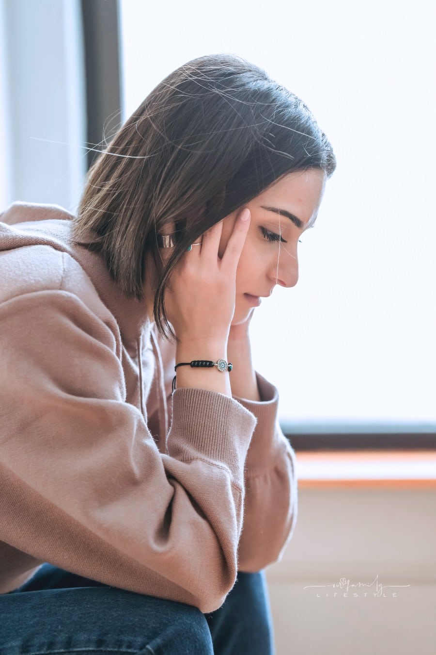 Sad woman with hands on head in room
