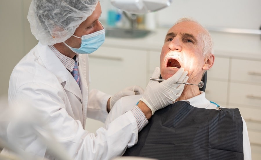 dentist looking into elder man's mouth