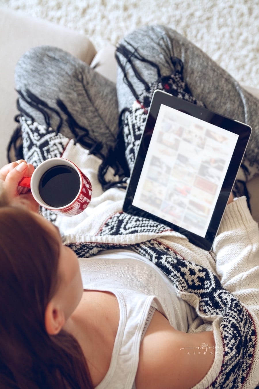 Woman reading news on tablet while drinking a cup of coffee