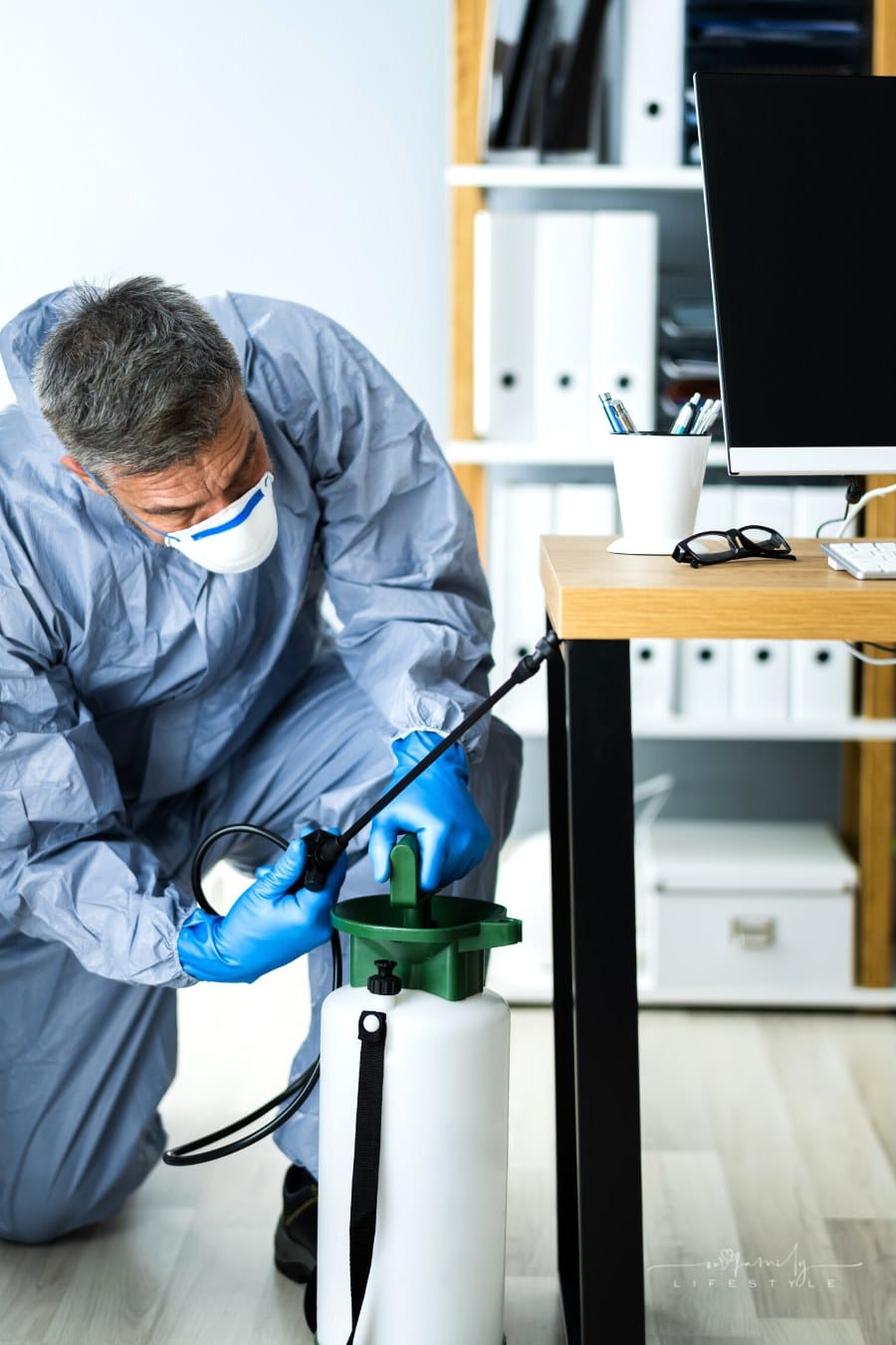 pest control exterminator spraying under desk