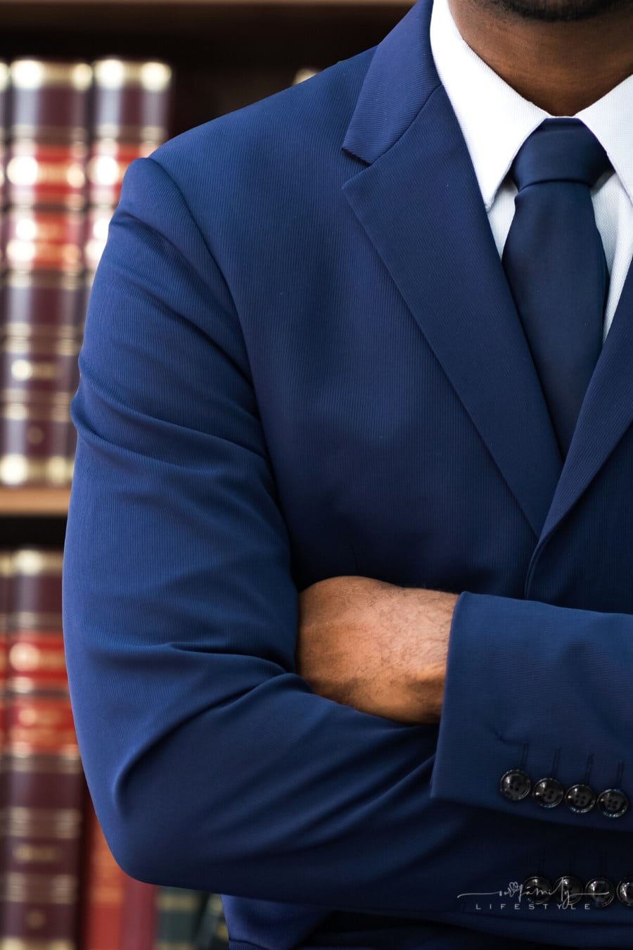 lawyer standing in front of bookcase with arms crossed