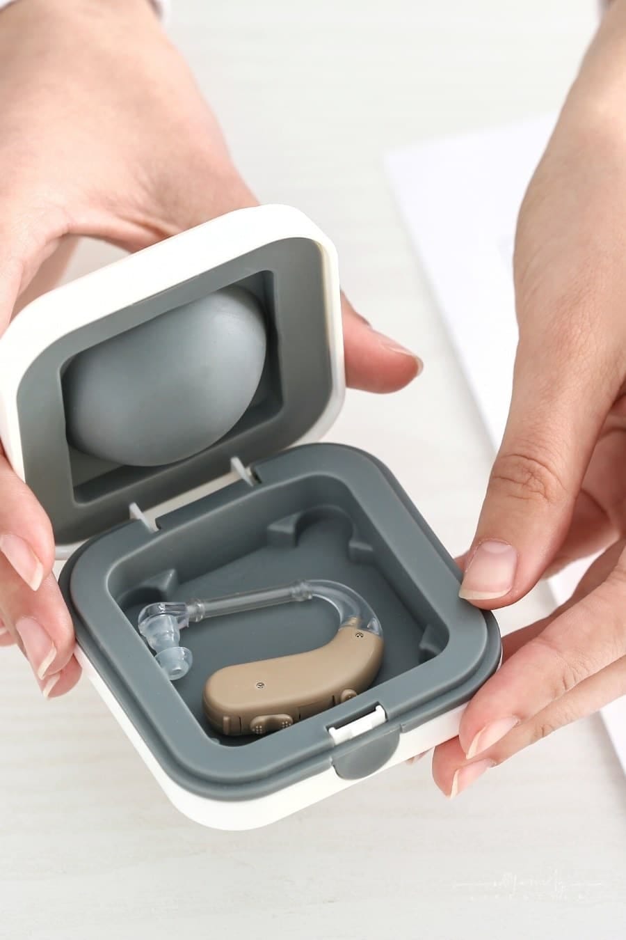 female doctor holding box with hearing aids