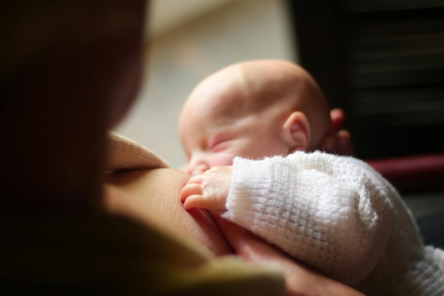 A close-up view of a mother breastfeeding her newborn baby, capturing a tender and intimate moment.
