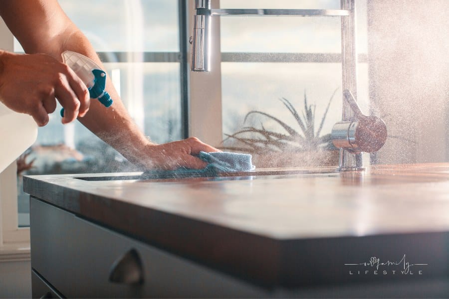 Cleaning kitchen with homemade insecticide product from a bottle.