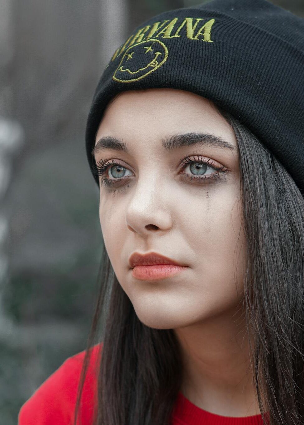 A contemplative young woman in a beanie, captured with a moody tone.