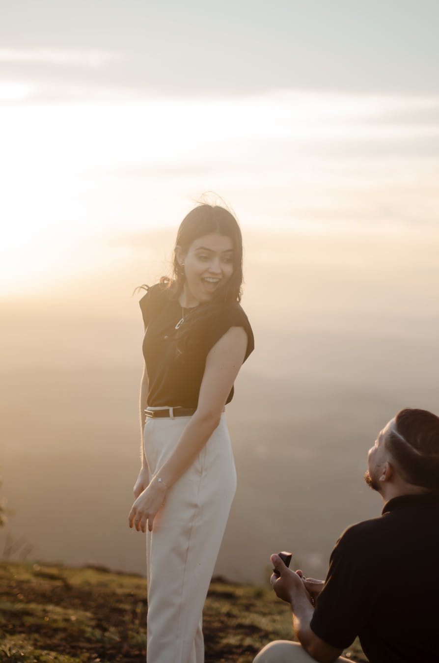 A couple's engagement on a hilltop at sunset, capturing a romantic moment.