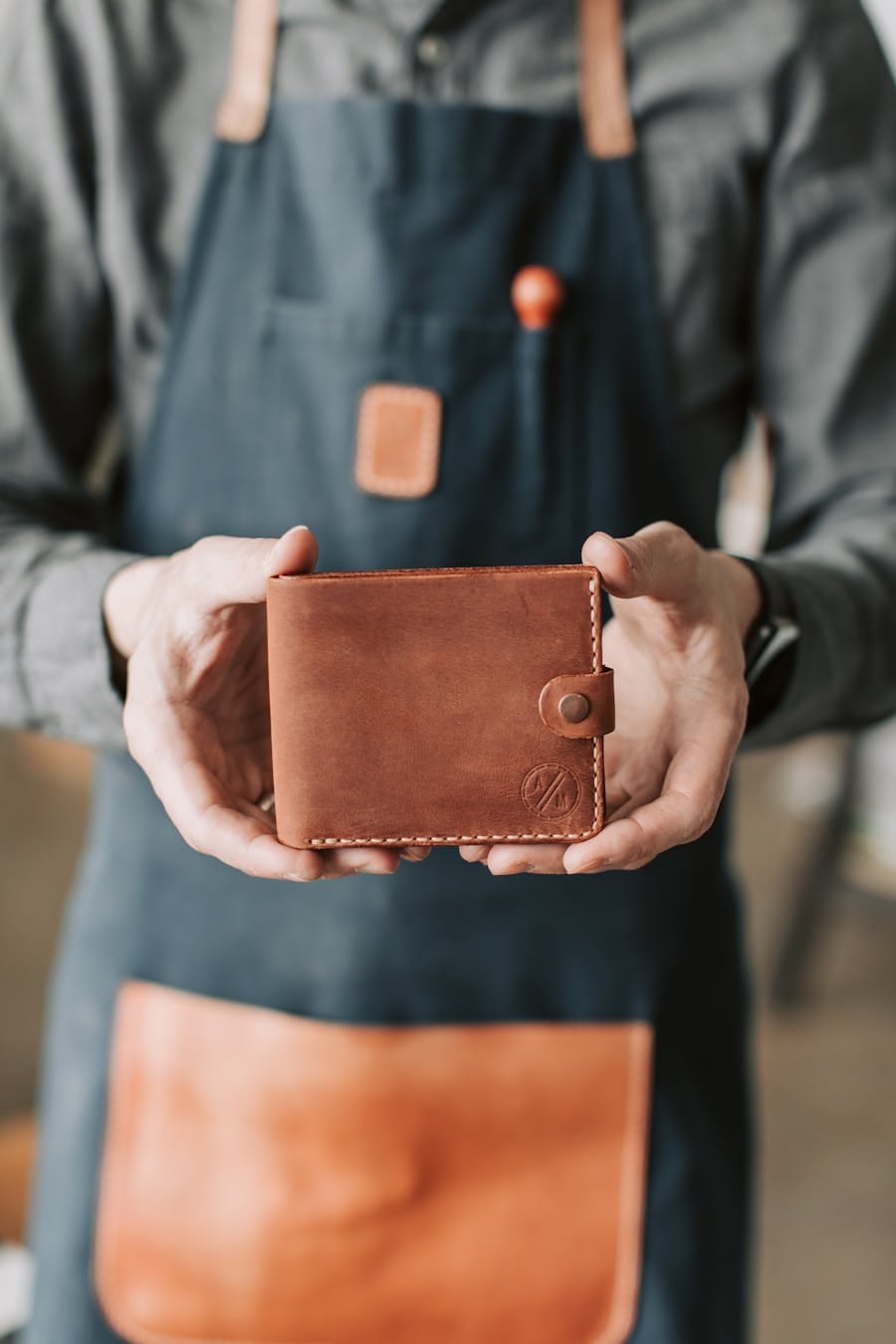 A craftsman holding a handmade leather wallet, showcasing artisanal craftsmanship.