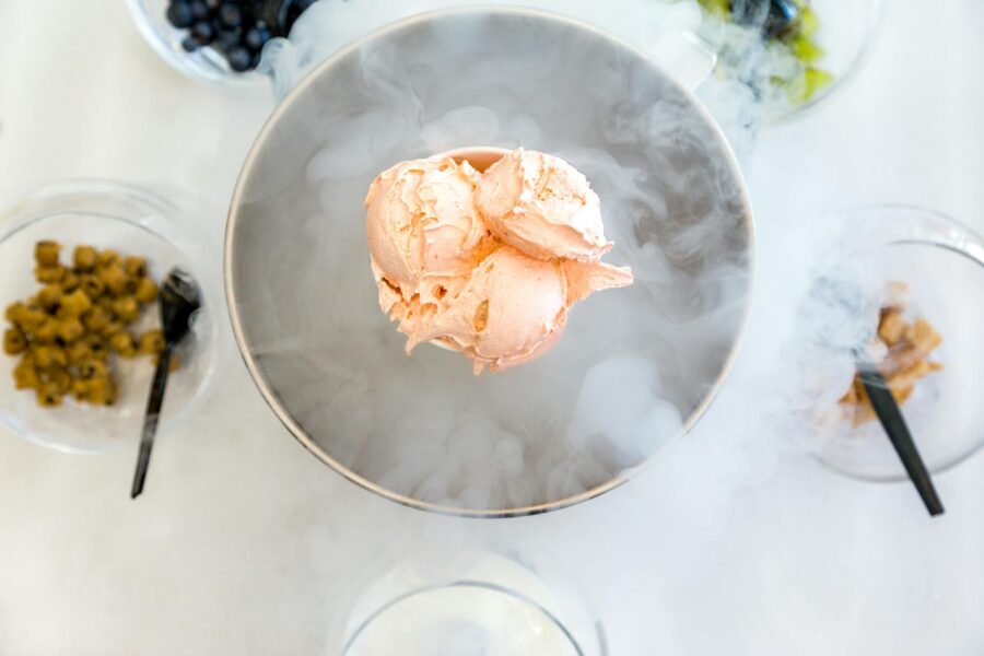 A creamy serving of nitrogen ice cream with various toppings, creating a smoky effect.
